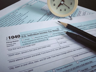 Tax-filling concept - A pencil, a pen, a clock and featuring half of U.S IRS 1040 form. With vintage-styled background.