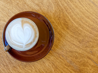 brown cappuccino coffe cup top view close up on natural wooden table surface, some space for text