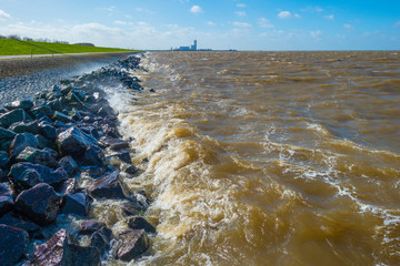 Water rising from a storm along a dike in a lake in sunlight in winter