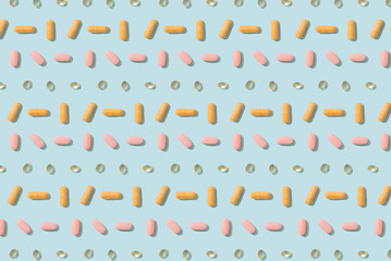 Colorful capsule pills and tablets pattern on a blue background. Cover, pharmacy, drugs, medicine backdrop. Top view