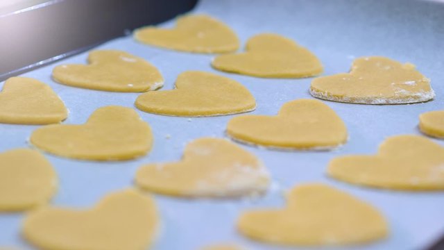 Tracking shot over the baking sheet with baked cookies. Sweet cookies in the form of heart.  Movement of the camera on top of the baking tray with fried cookies, close up view. 4k slow motion footage
