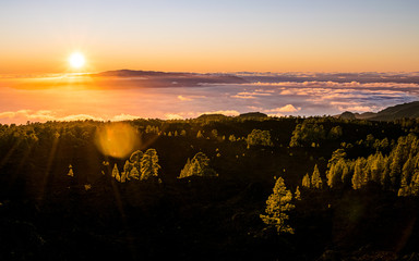 Obraz premium Gorgeous colorful sunset over the sea of clouds in Tenerife, with the La Gomera island on the horizon. Scenic landscape of Canary Islands, Spain. 