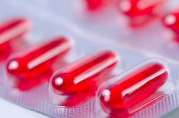 Red pills capsule medicine and pharmacy macro blur background