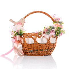 Fototapeta na wymiar Basket with delicate handmade decor. Decorated with pink little flowers, greenery, wooden bird and wide pink ribbon with big bow. Isolated on white background