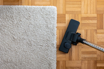 Vacuum cleaner extension on a laminated wooden floor next to a grey fabric rug
