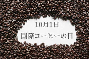 コーヒー豆で囲まれた白紙に日本語の10月1日国際コーヒーの日の印刷文字