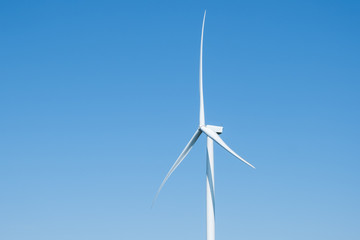 Electricity generating wind turbines with blue sky in background