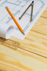 Rolled house diagrams and accessories for drawing lying on construction drawing and wooden boards