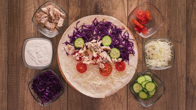Making a kebab or gyros - a traditional roll sandwich wrapped in wheat flour wraps and various fresh ingredients - top view, flat lay