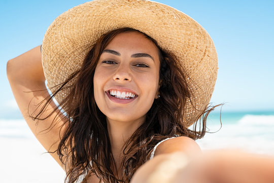 Beautiful tanned woman at beach wearing straw hat