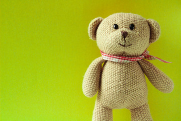 Brown teddy bear, toy is standing on a light green background, close up.