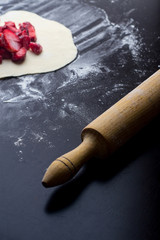 red strawberries on pastry with flour on a black table