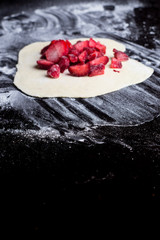red strawberries on pastry with flour on a black table