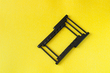 black folding phone holder, on a yellow background
