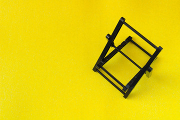 black folding phone holder, on a yellow background