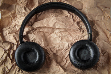 Black wireless headphones. Overhead, isolated professional-grade headphones. View from above. On a textured beige background.