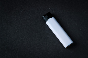 White plastic gas lighter. Gas lighter on black background. Closeup shot, top view