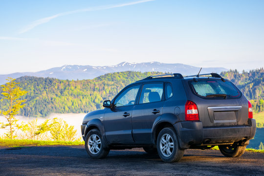 suv on the edge of a mountain. beautiful view in to the distant valley full of fog. ridge in the distance. fantastic springtime scenery in the morning. travel by car concept
