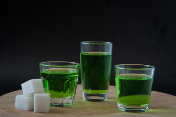 Strong alcohol. three shot glasses with absinthe, with white sugar. on a black background
