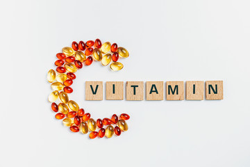 letter C made from transparent pills near the inscription Vitamin on a white background