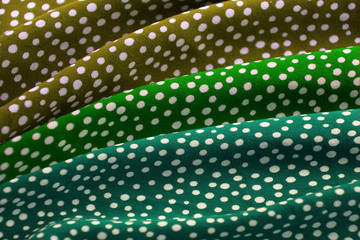 beautifully draped with soft folds bright green, fabric for needlework or decor, polka dot texture and dots, close-up, copy space