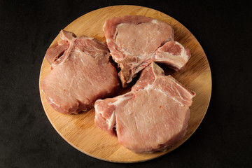 three pieces of raw meat, steaks, on a wooden board