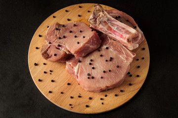 three steaks on a wooden board, raw meat with pepper