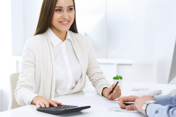 Business woman and man sitting and working with computer and calculator in office. Bookkeeper or accountant checking balance or making finance report. Tax and audit concepts