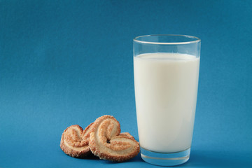 glass of milk and cookies, heart-shaped cookies, on blue background