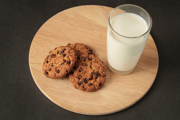 glass of milk and oatmeal cookies on a wooden board