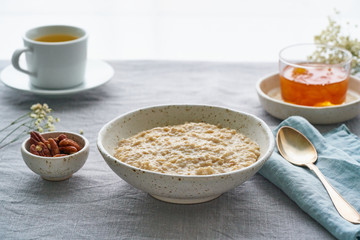 Whole oatmeal, large bowl of porridge with butter for breakfast, morning meal. Side view