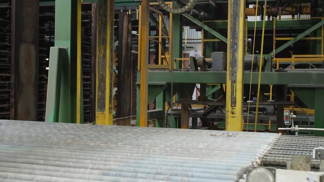 Close up of conveyer belt and the maching mechanism moving down at the factory. Stock footage. Professional equipment at the manufacturing plant.