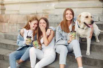 Beautiful girls drinking a coffee. Women in a spring city. Ladies with cute dog.