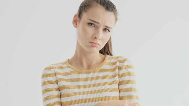 An upset young woman is showing like a tear falls down from her eyes isolated over white background in studio