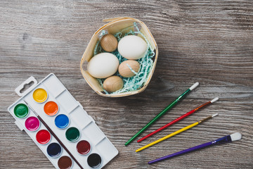 easter eggs in nest and colorful paints and brushes