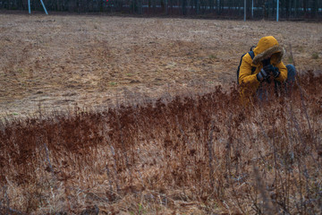 Photographer in the field shoots grass, flowers.
