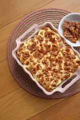 Italian dessert Tiramisù with caramel syrup and  peanut brittle pieces on wooden table 