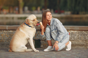 Beautiful girl in a park. Stylish girl in a jeans jacket. Lady with a dog