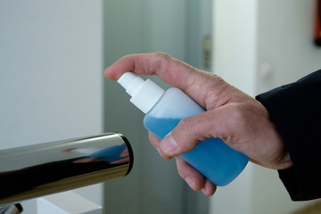 man disinfecting the handrail of a stairway.