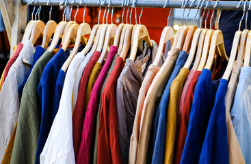 The store has a lot of colorful t-shirts hanging on a hanger. a row of t-shirts hangers in the store. t-shirt sales