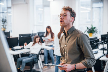Man in glasses standing in front of his colleagues in the office