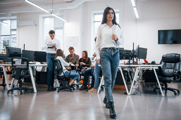 Fototapeta premium Beautiful young girl indoors in office against her coworkers in the office