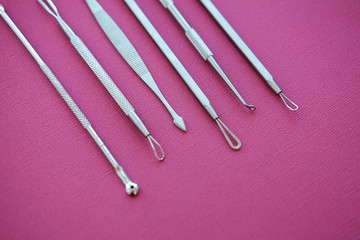 Tools for removing acne. Tools of the cosmetologist for problem skin on pink paper background.