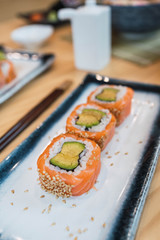 Pieces of salmon and avocado sushi served on a white ceramic plate