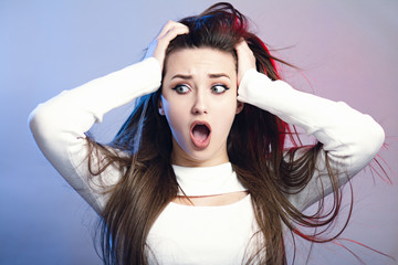portrait of a beautiful shocked girl with long hair on studio background, a young woman opened her mouth in surprise, concept female emotions