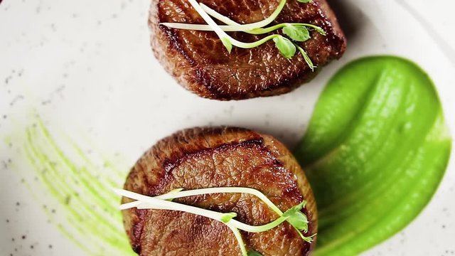 Filet mignon steak with mashed green peas and green pea sprouts, top view.