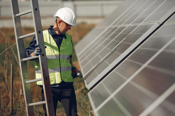 Engineer in a white helmet. Man near solar panel. Worker with a ladder © hetmanstock2