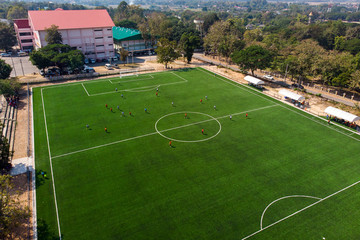 Aerial drone top view of mini football soccer field with playing people.