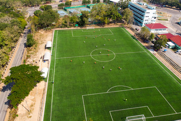 Aerial drone top view of mini football soccer field with playing people.