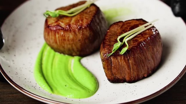 Filet mignon steak with mashed green peas and green pea sprouts.